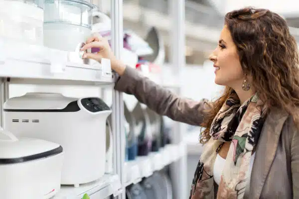 Female consumer comparing small appliance designs for aesthetic usability at store